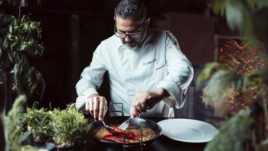 Alejandro Bello prepara un plato rodeado de vegetación en el restaurante.