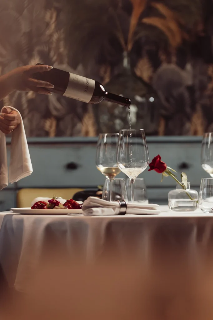 Servicio de vino en una mesa vestida con mantel blanco y copas.