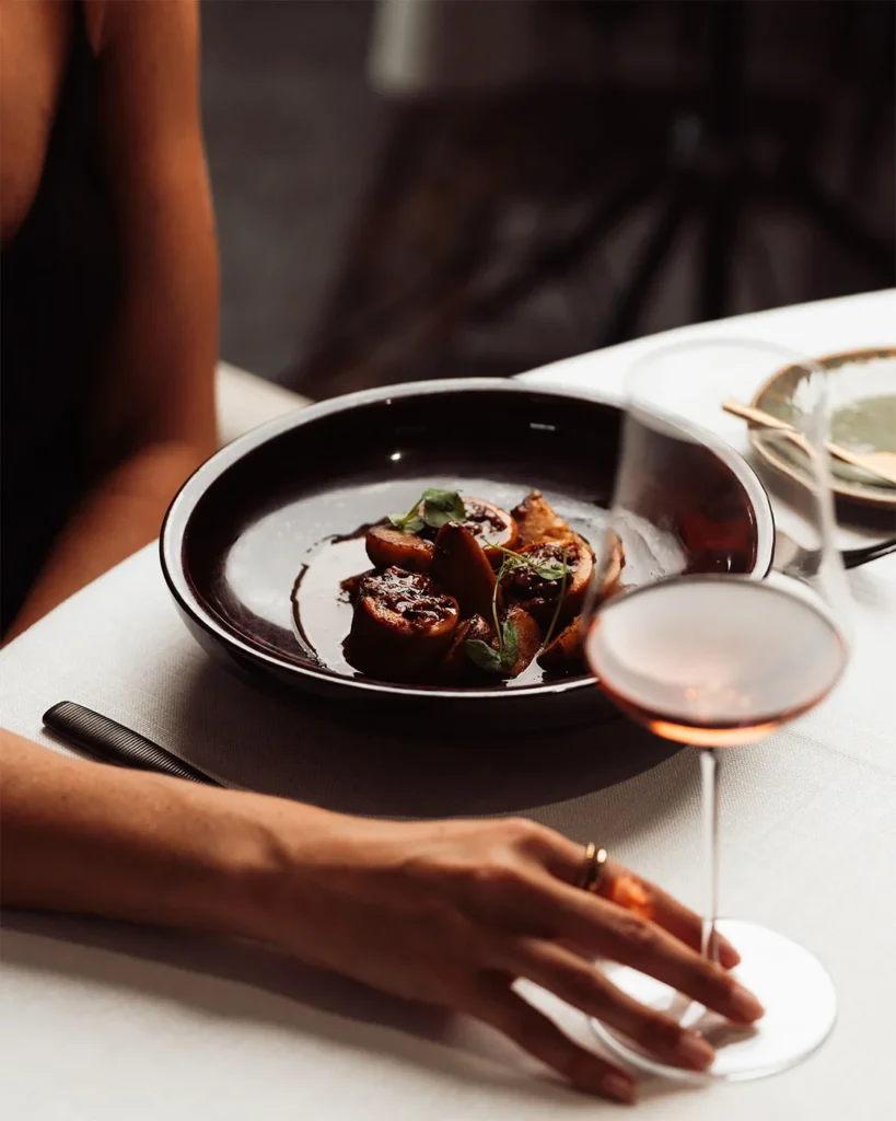 Plato de cerámica oscura servido junto a una copa de vino en El Lajar de Bello.