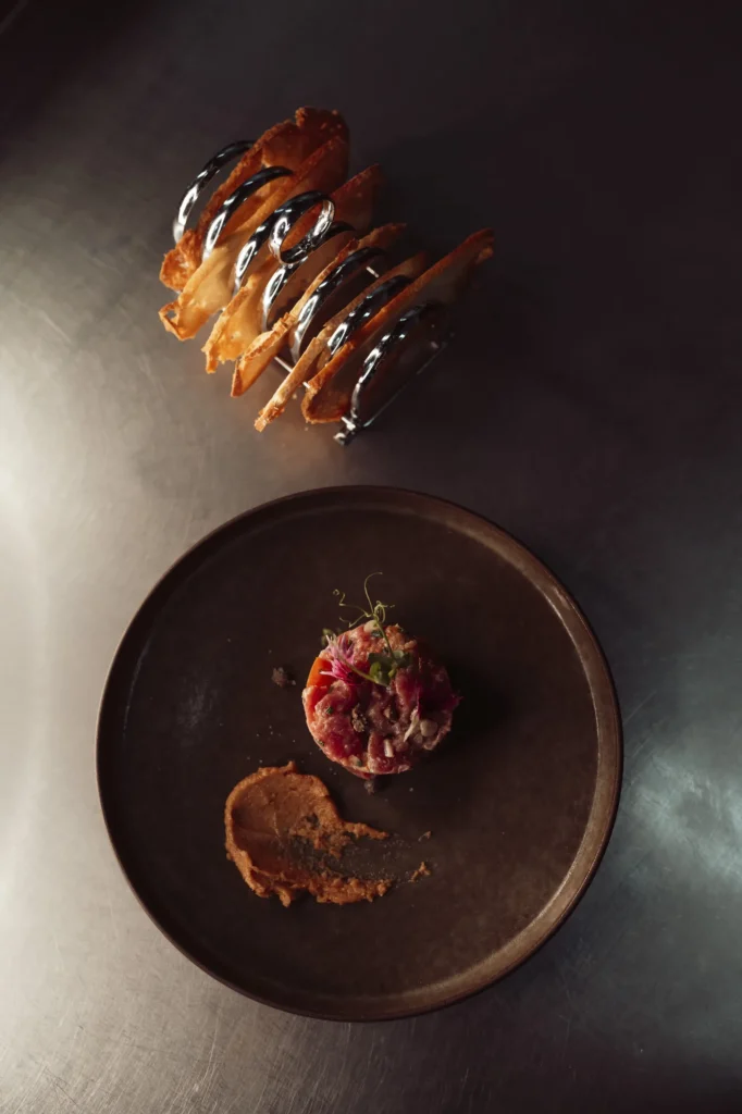 Presentación gastronómica en un plato oscuro sobre fondo de piedra.