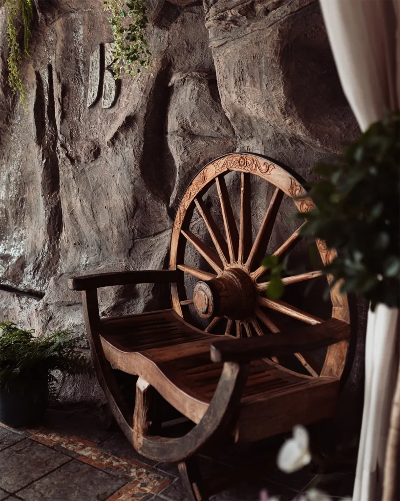 Rincón de piedra con una rueda de madera decorativa en El Lajar de Bello.